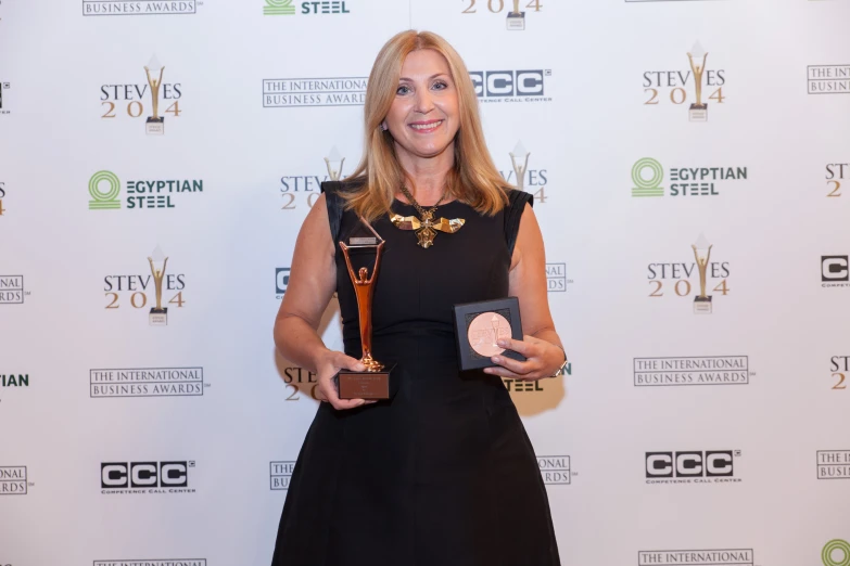 a woman in a black dress holding an award