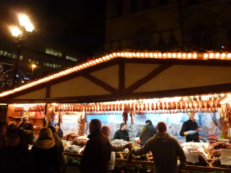 people are gathered around an outdoor market at night