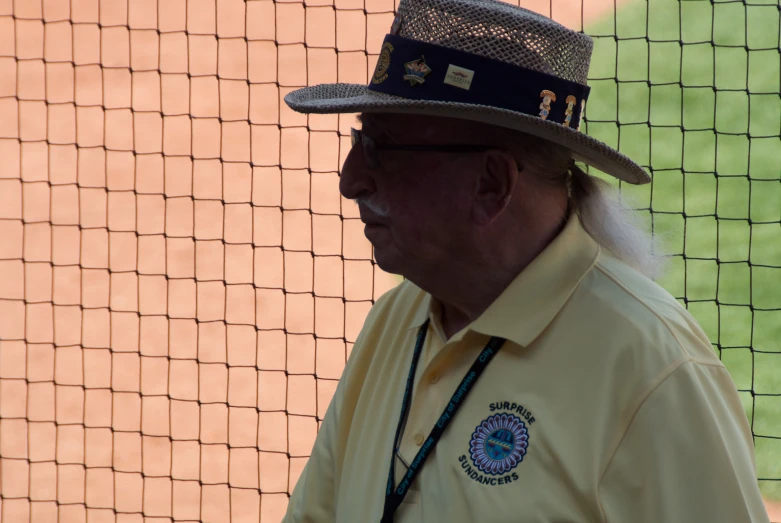 an older man wearing a hat in front of a net