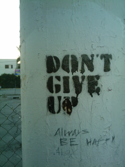 a graffiti is spray - painted on a wall saying don't give up