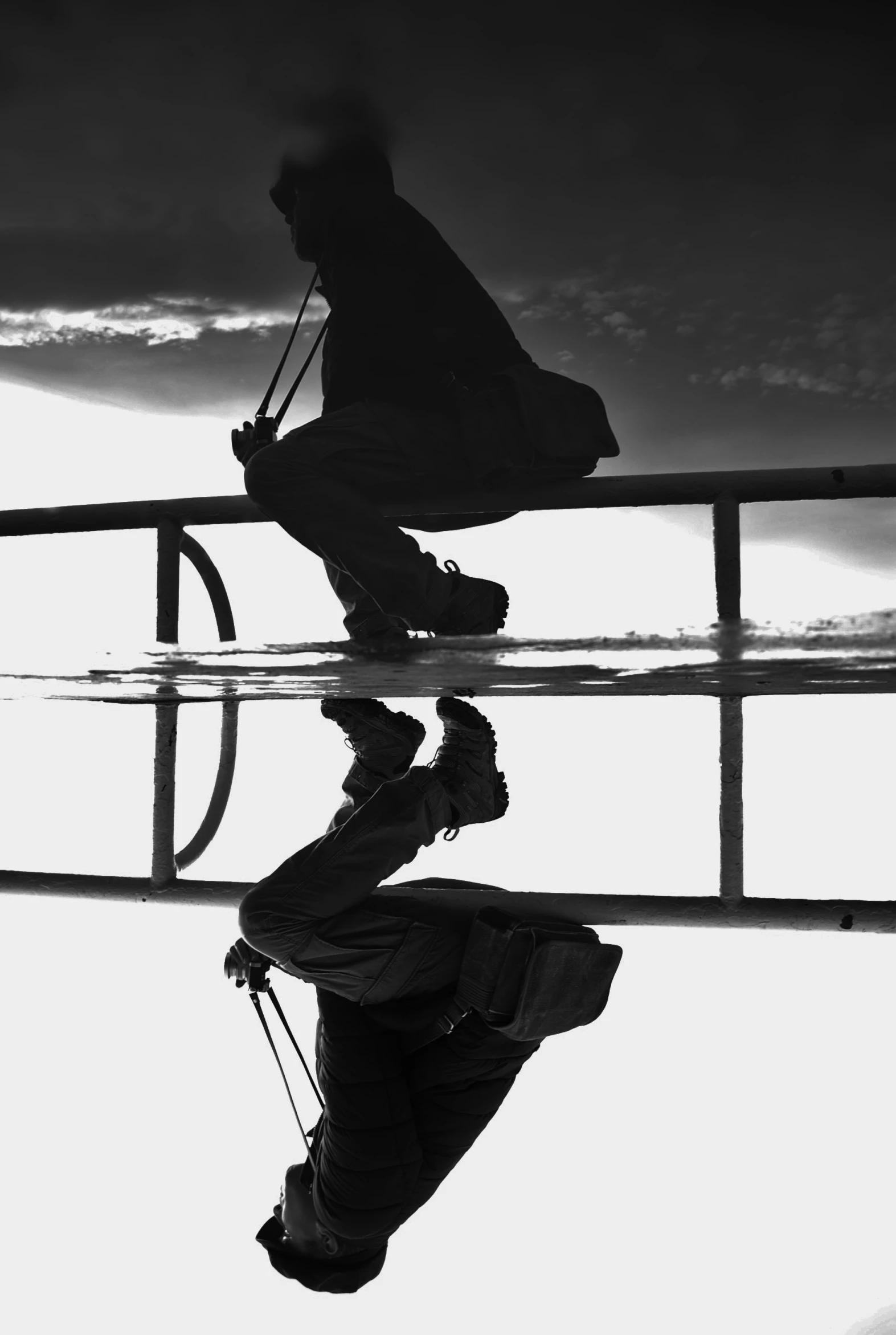 two people sit on the edge of the pier as they hold umbrellas