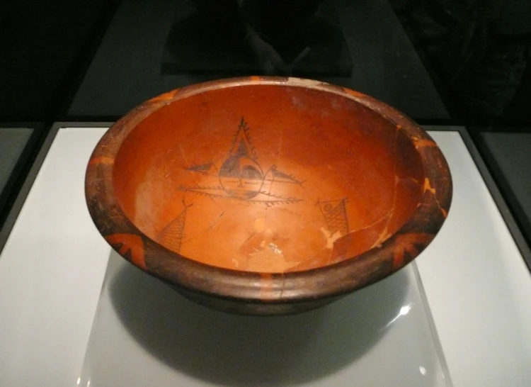 a brown bowl on display in a glass case