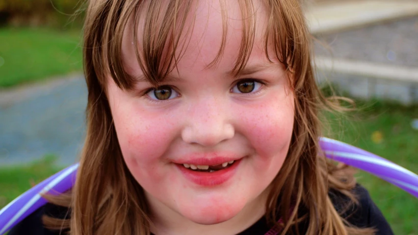 a little girl standing in a yard wearing a blue tee