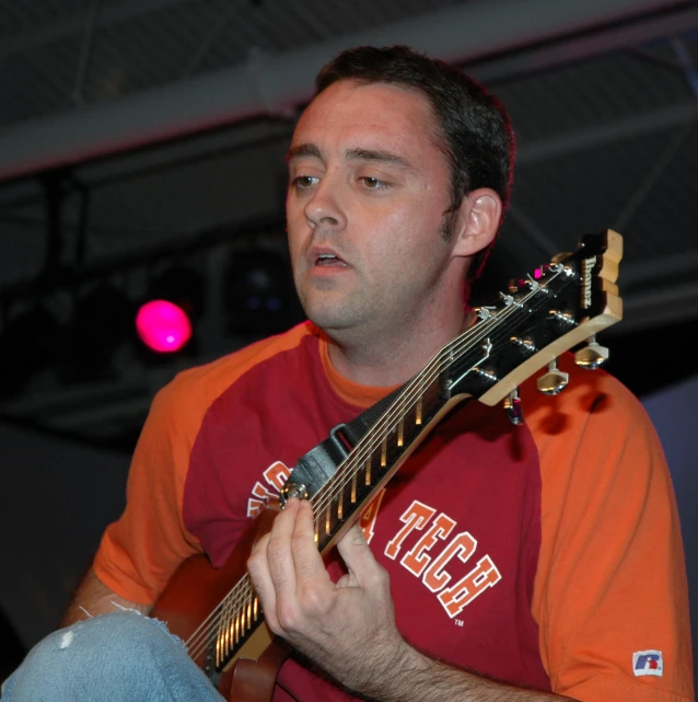 a man playing an acoustic guitar while looking at the audience