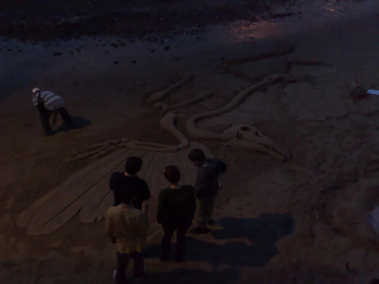 several men are looking at a drawing in the sand