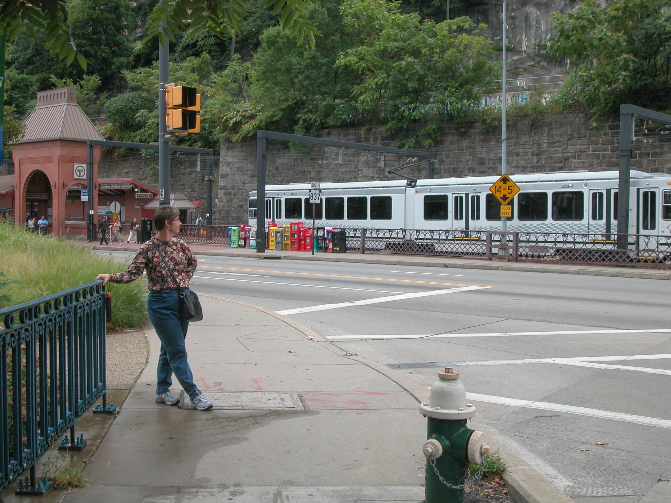 the person walks on the sidewalk in front of a large white passenger train