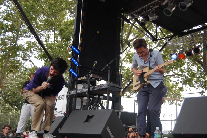 two young men are playing guitar and singing