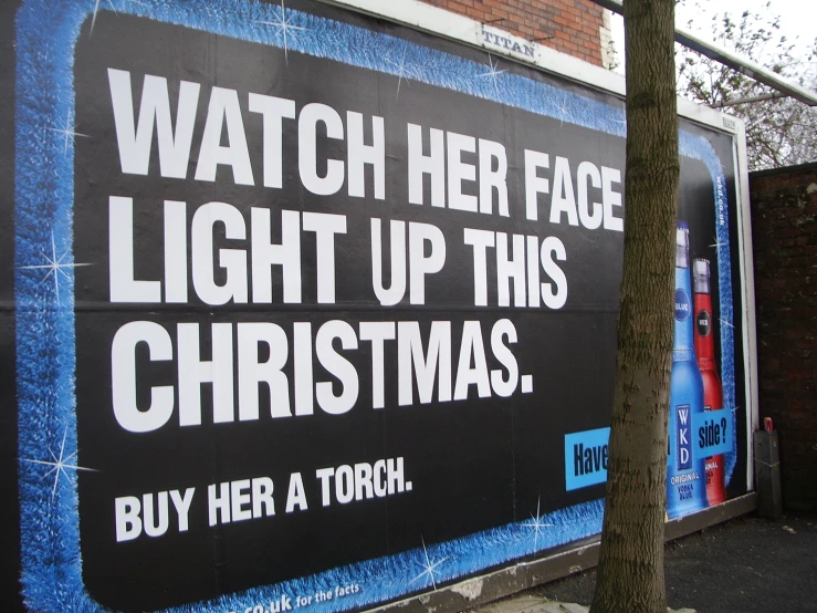 a large sign advertising christmas in front of a brick wall