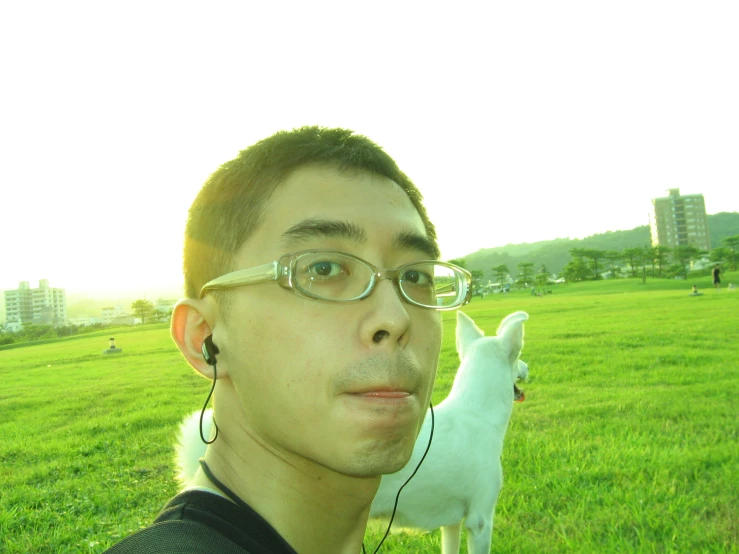 young man listening to ear buds with a dog nearby