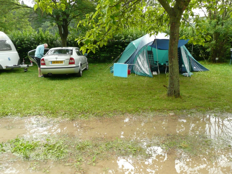 several tents set up beside a parked car