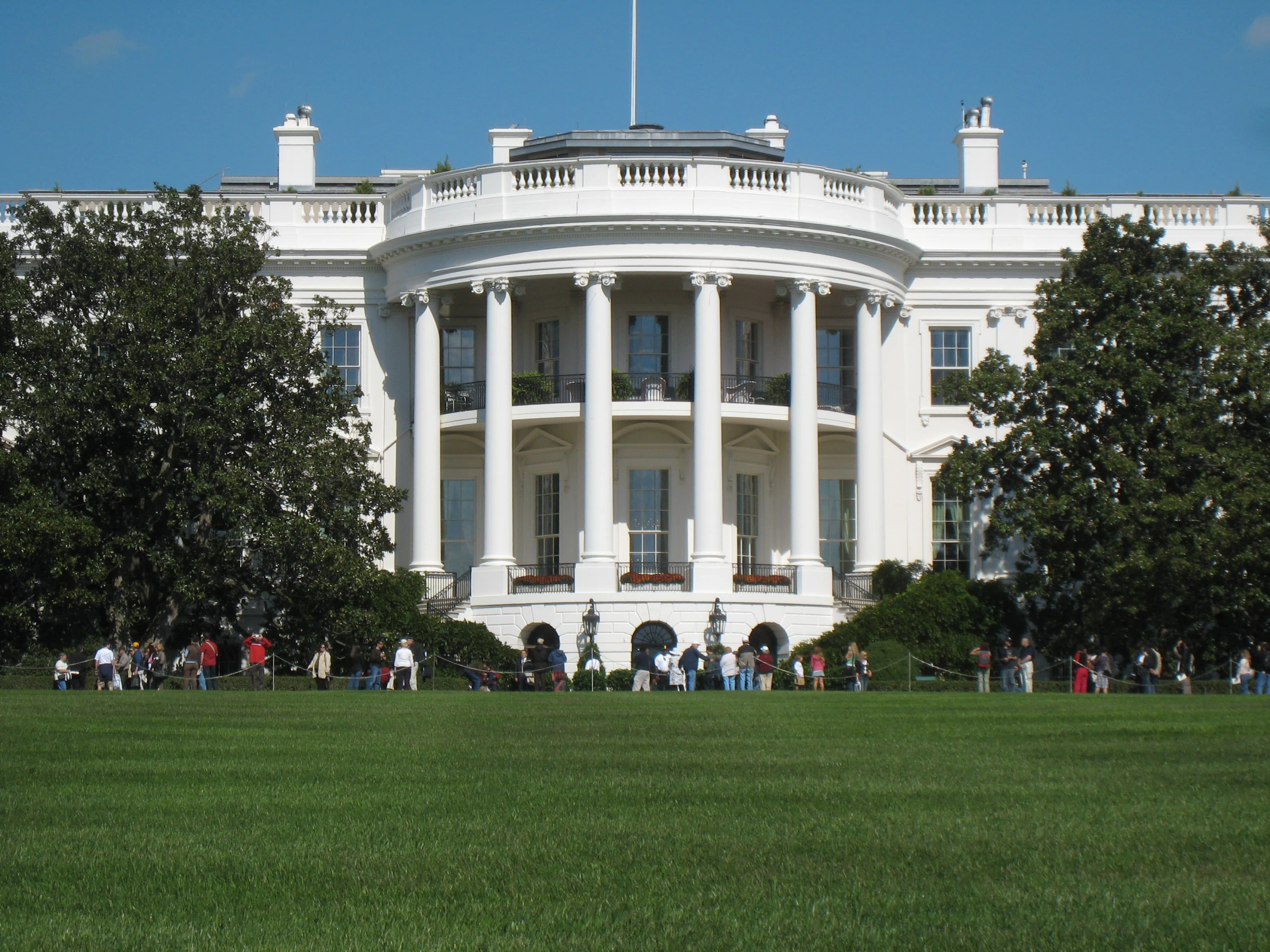 people standing around the white house in front of it