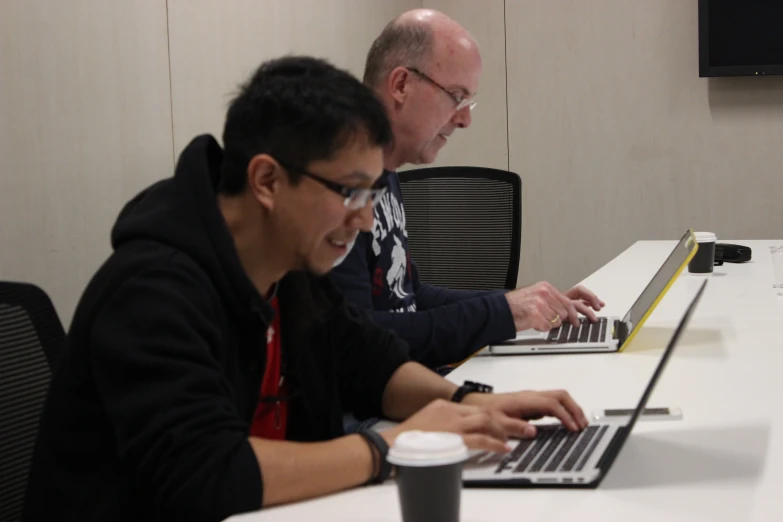 two people working on a laptop computer at a conference table