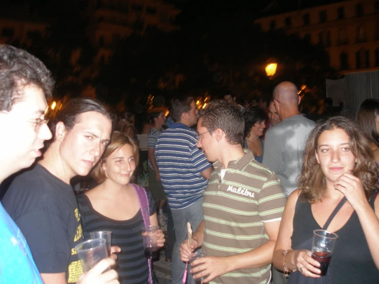 a group of people outside at night drinking drinks