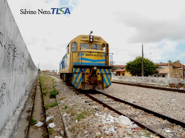 an old yellow train is shown going past a building