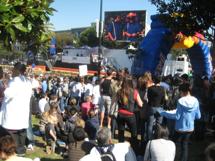 a large group of people standing around watching soing on screen