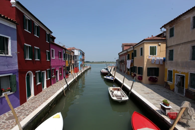 several boats are in a narrow canal beside some houses