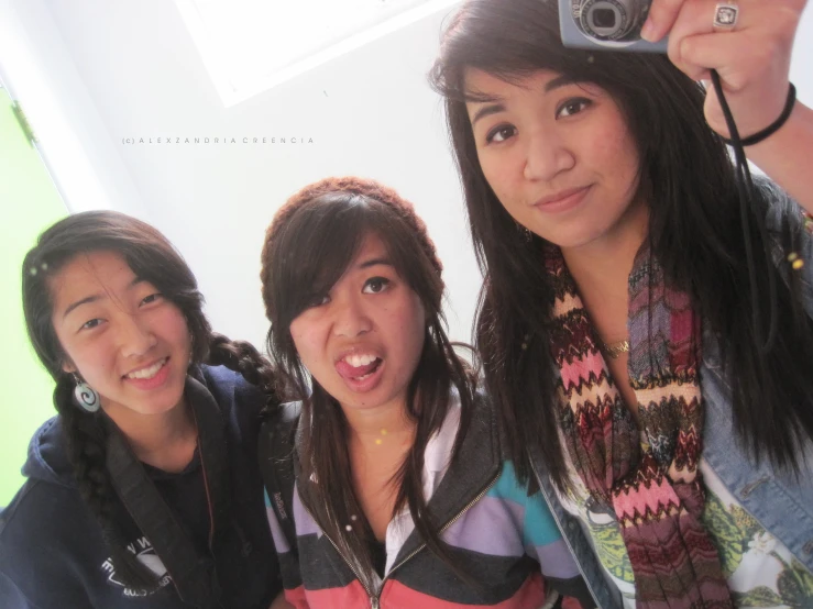 three young women posing for the camera with one taking a picture