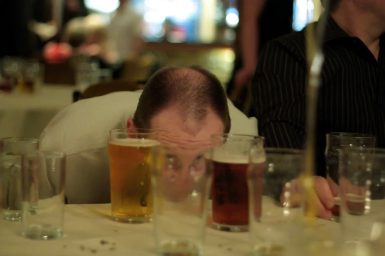 a man sitting down at a table with a bunch of glasses and beer