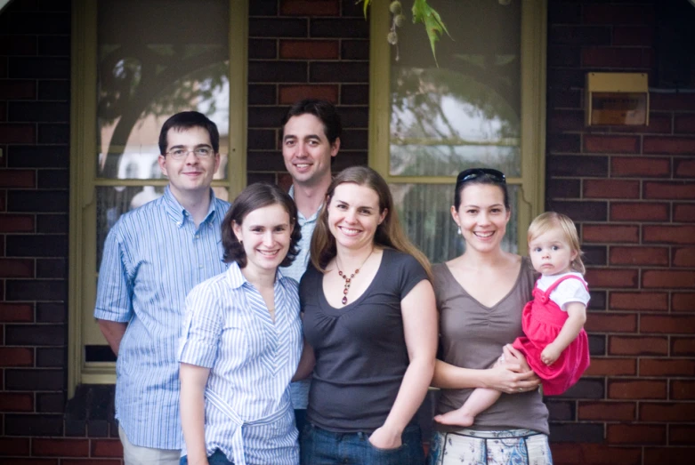 a large family poses outside of a brick house