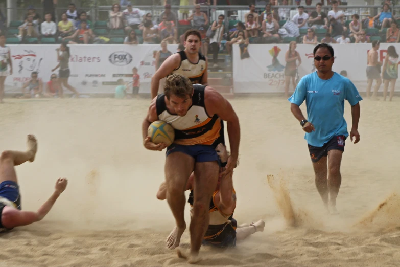 some men that are playing in a beach sand soccer game