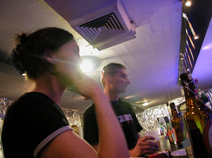 a man and woman stand in a bar talking