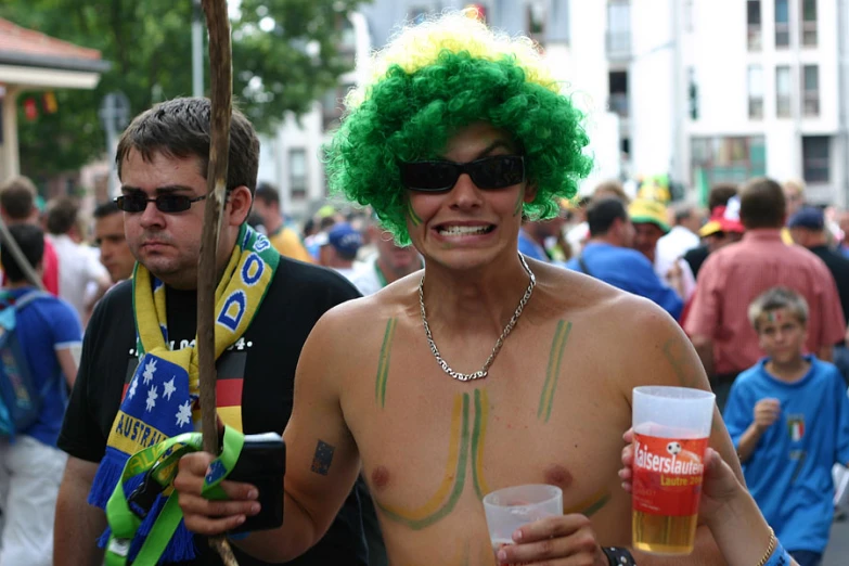 a guy with curly hair and green hair holding beer and standing next to another guy