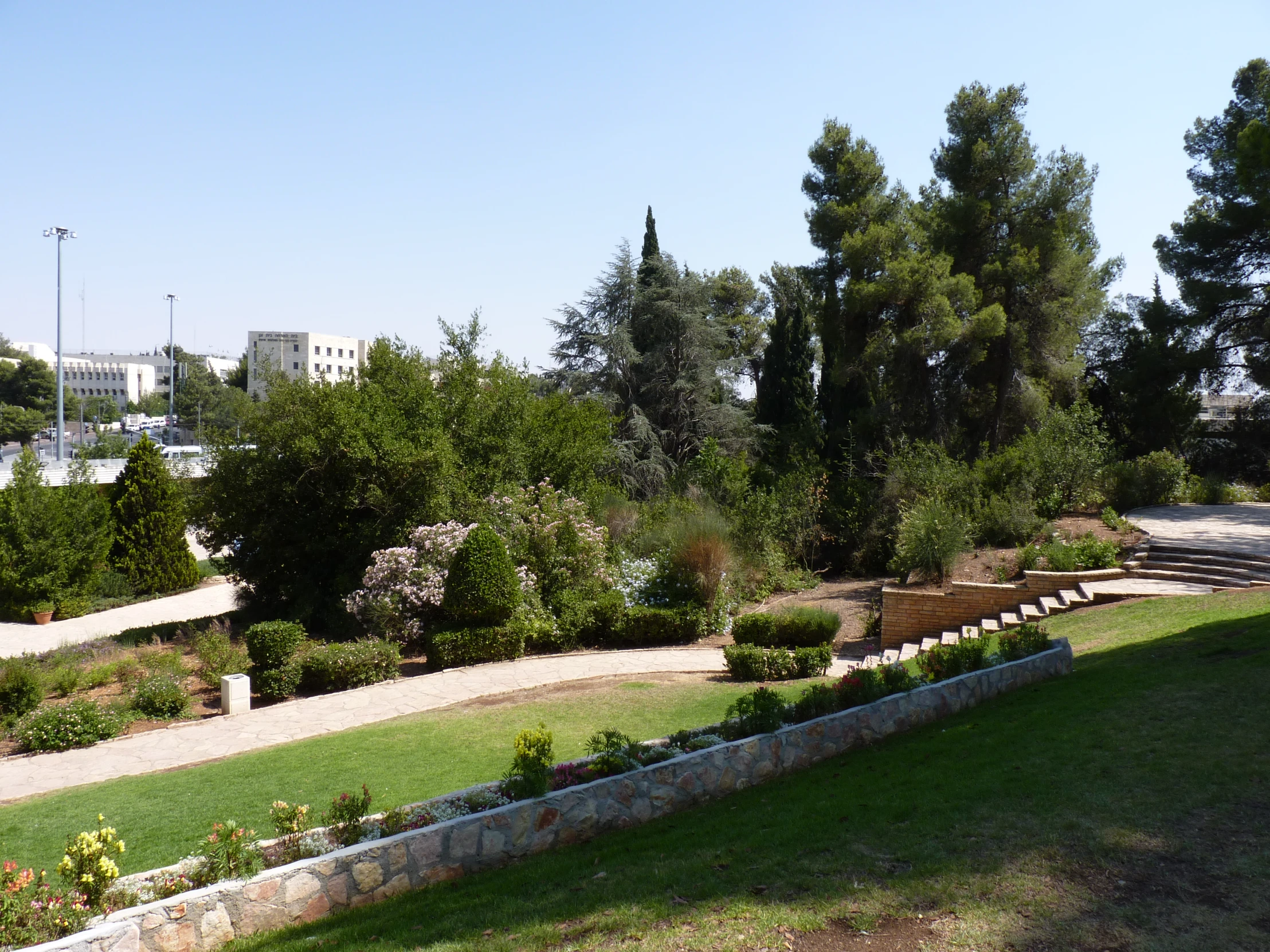 a grassy area surrounded by several benches, trees and rocks