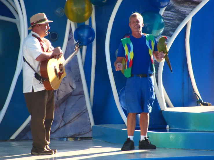 two men singing and playing guitar in front of balloons