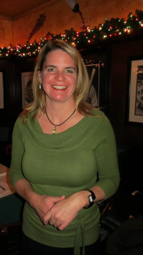 woman wearing light green sweater, smiling with arms crossed