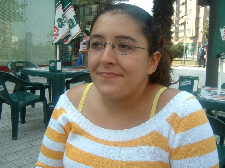a woman in glasses sitting at an outdoor restaurant