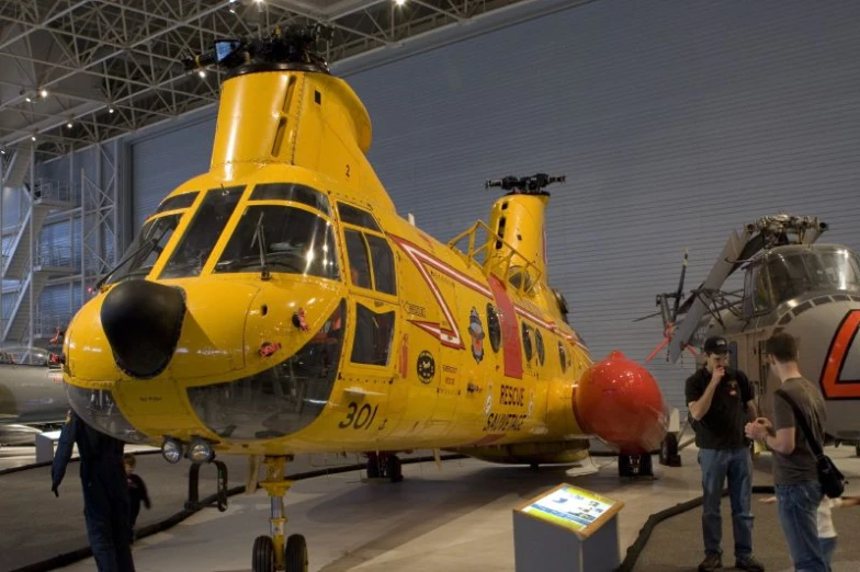 a helicopter in a hangar surrounded by people