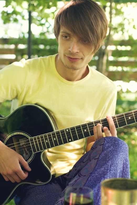 a man playing an acoustic guitar outside on a table