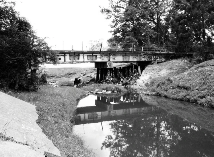 a black and white po of a river with a bridge