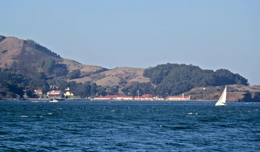 three boats on the water near a large hill