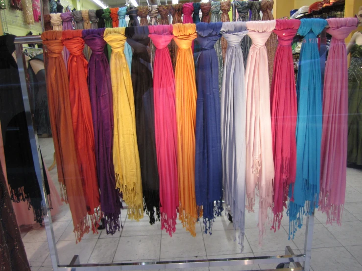 a rack in a store filled with assorted colored scarves