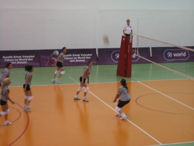 a group of girls playing volleyball in an indoor court