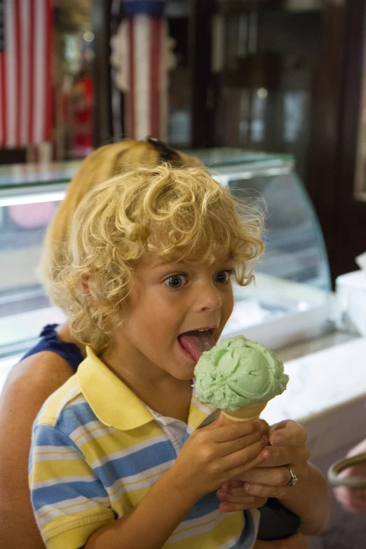 a small child holds up a piece of ice cream