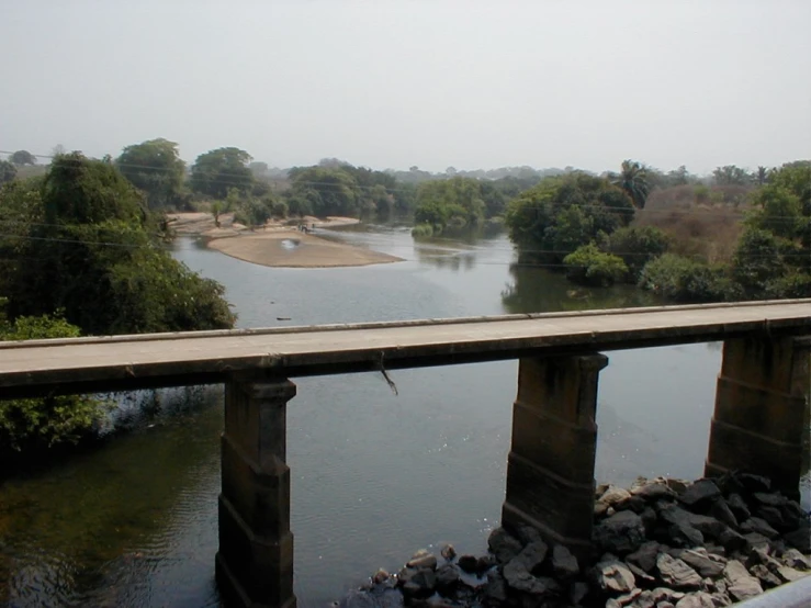 a bridge spans over a body of water with many trees in the distance