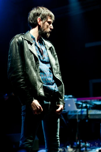 a man wearing a leather jacket on stage