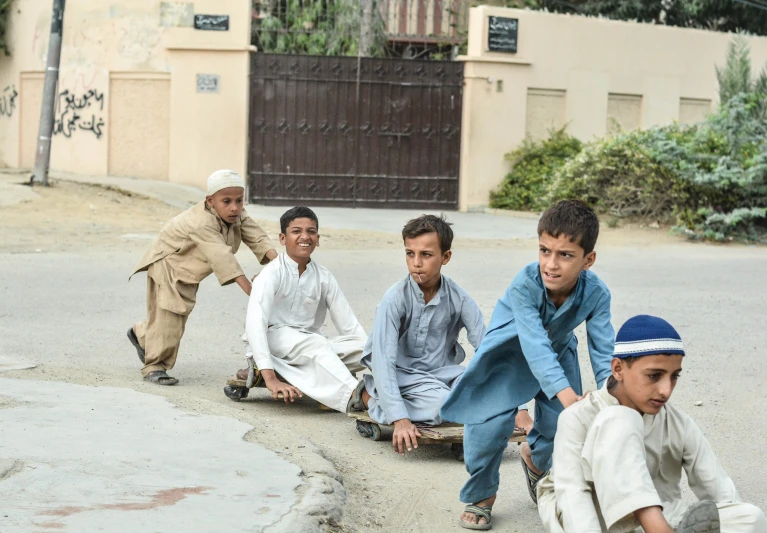 a group of s sitting on the ground in front of some buildings
