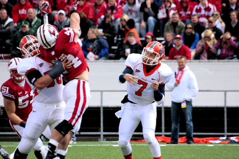 a football player throwing a ball with another player trying to block