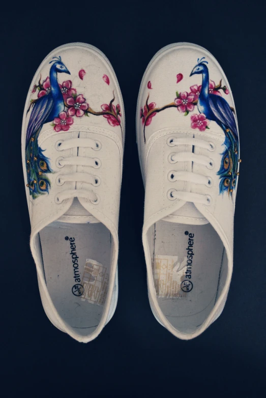 a pair of white shoes with a blue bird on it