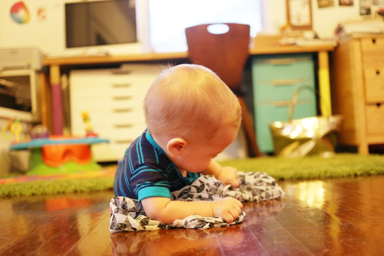 a toddler on the floor, wearing a blue and black outfit