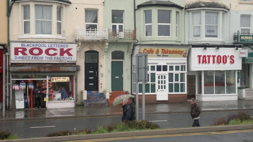 people standing in the rain in front of some businesses