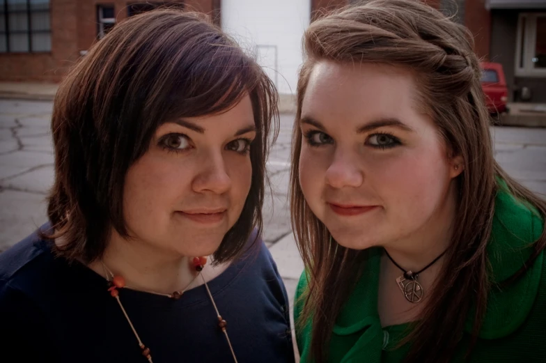 two young ladies standing next to each other near a building