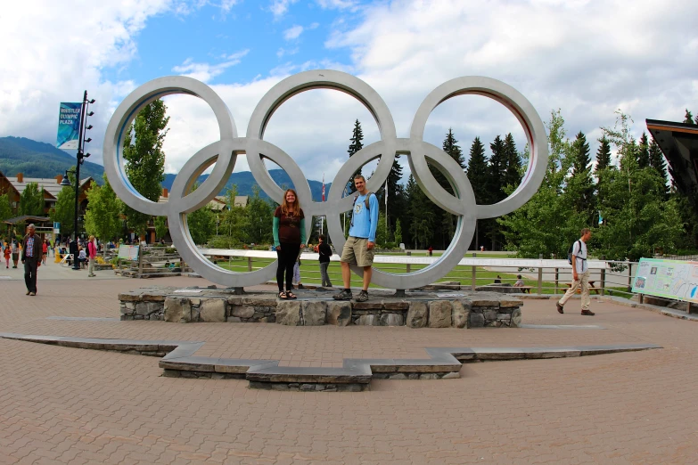 a couple stands near an olympic symbol