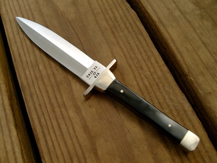 a knife sits on top of a wooden surface