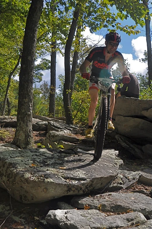 man riding bicycle up rocks in the woods