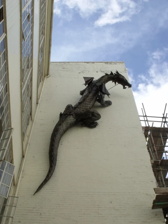 a large lizard laying on the side of a tall building