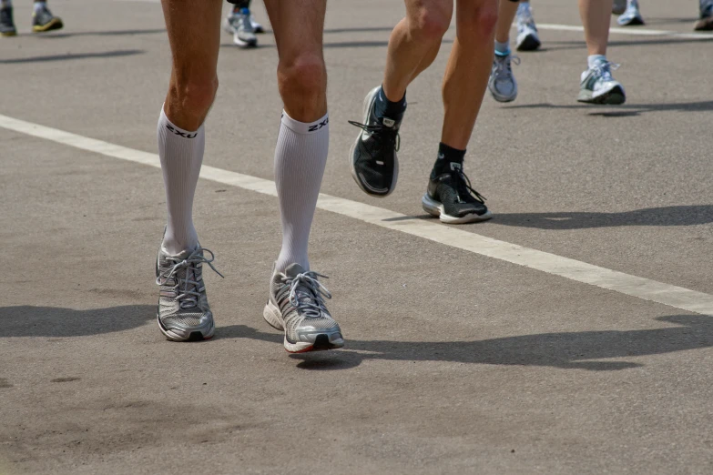 several legs and socks on the ground while people are running
